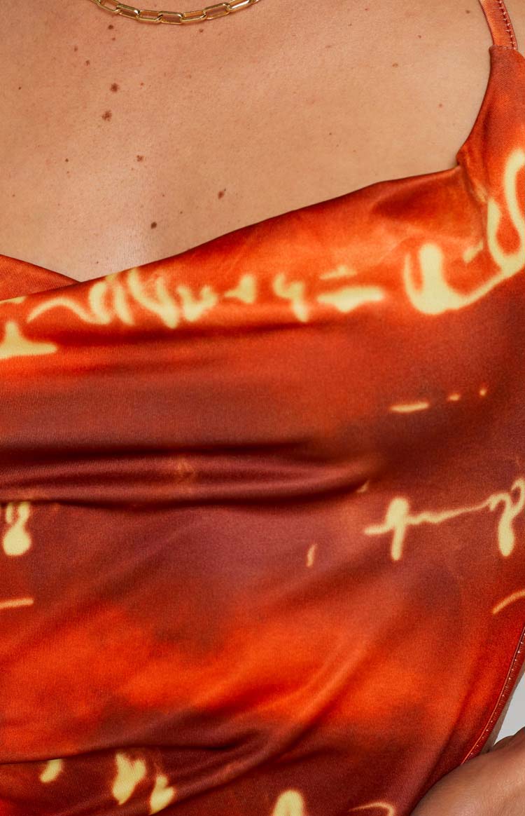 Side view of a red and orange abstract print halter mini dress with an open back and adjustable ruched ties
