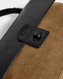 Close-up of the Rudsak ESMA - 8324519 Camel handbag, featuring suede leather with a black flap, matte clasp, embossed branding near the clasp, and a removable shoulder strap for versatile style.