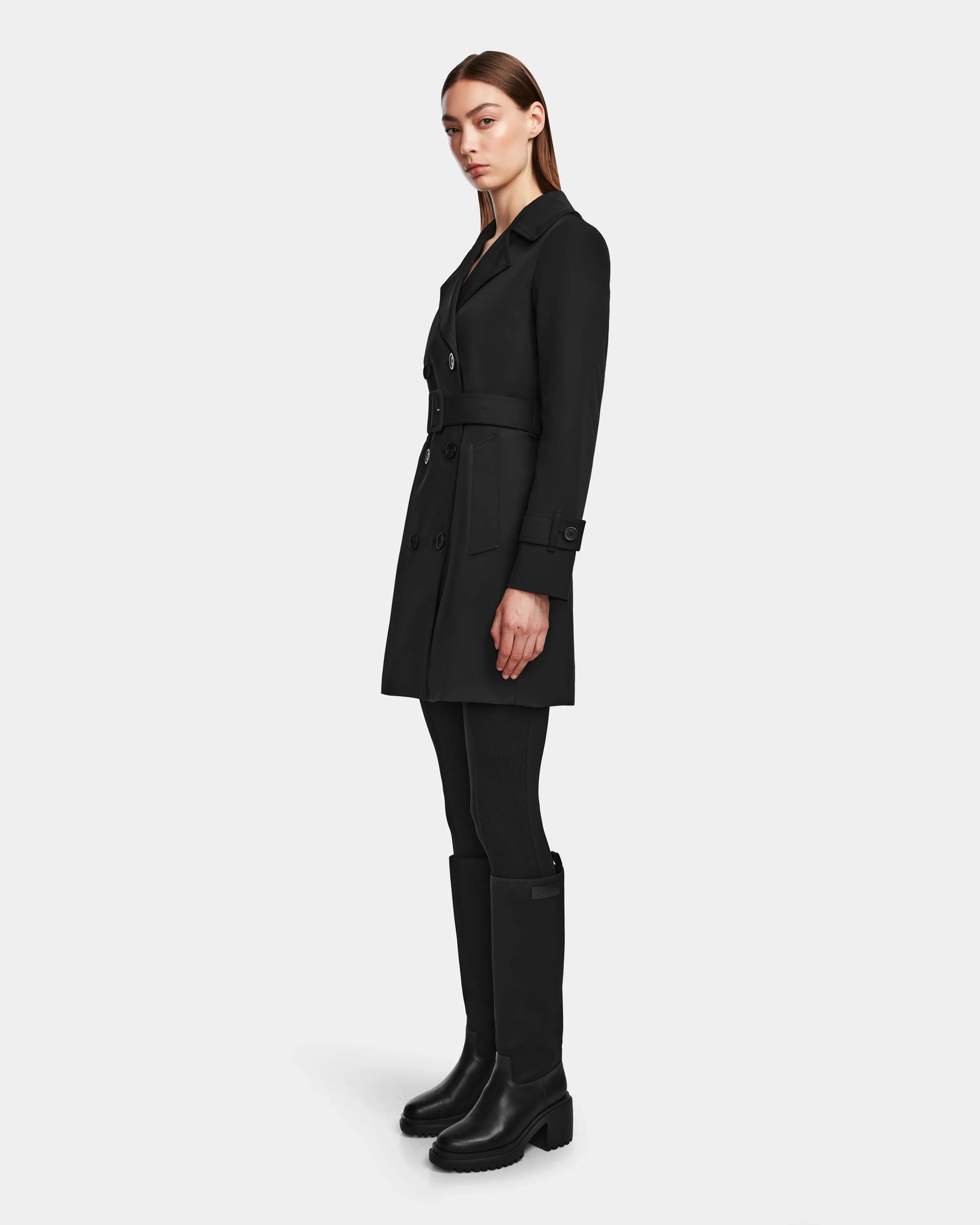 A woman in the Rudsak KIMBERLY - 8124801 Black womens belted trench coat.