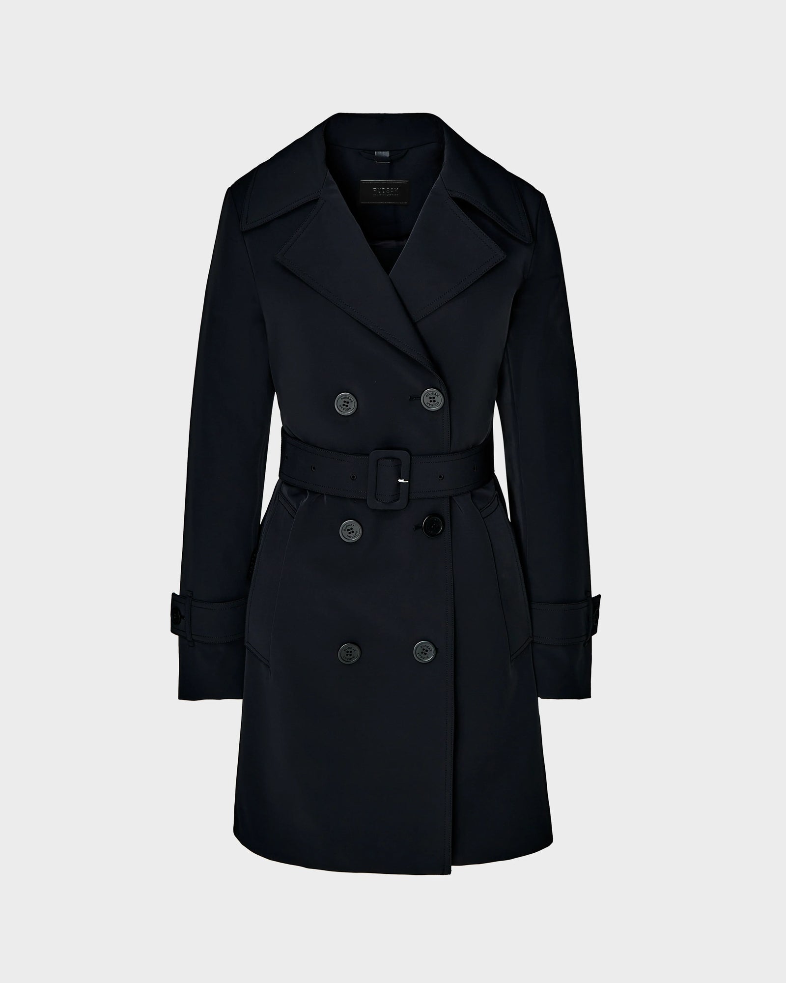The KIMBERLY - 8124801 Black by Rudsak is a women’s belted, double-breasted trench coat with wide lapels, button closures, and adjustable cuffs in water-repellent fabric. Shown on a light gray background.