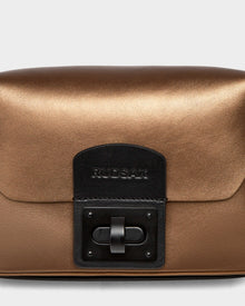 The OFILIA - 8324504 crossbody by Rudsak in antique bronze metallic leather features a black rectangular clasp and the Rudsak name embossed on the front flap.