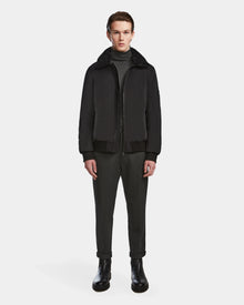 A person faces forward wearing the Rudsak REECE - 6124592 Black men’s bomber jacket with a shearling collar over a dark turtleneck, dark pants, and black boots against a plain white background.
