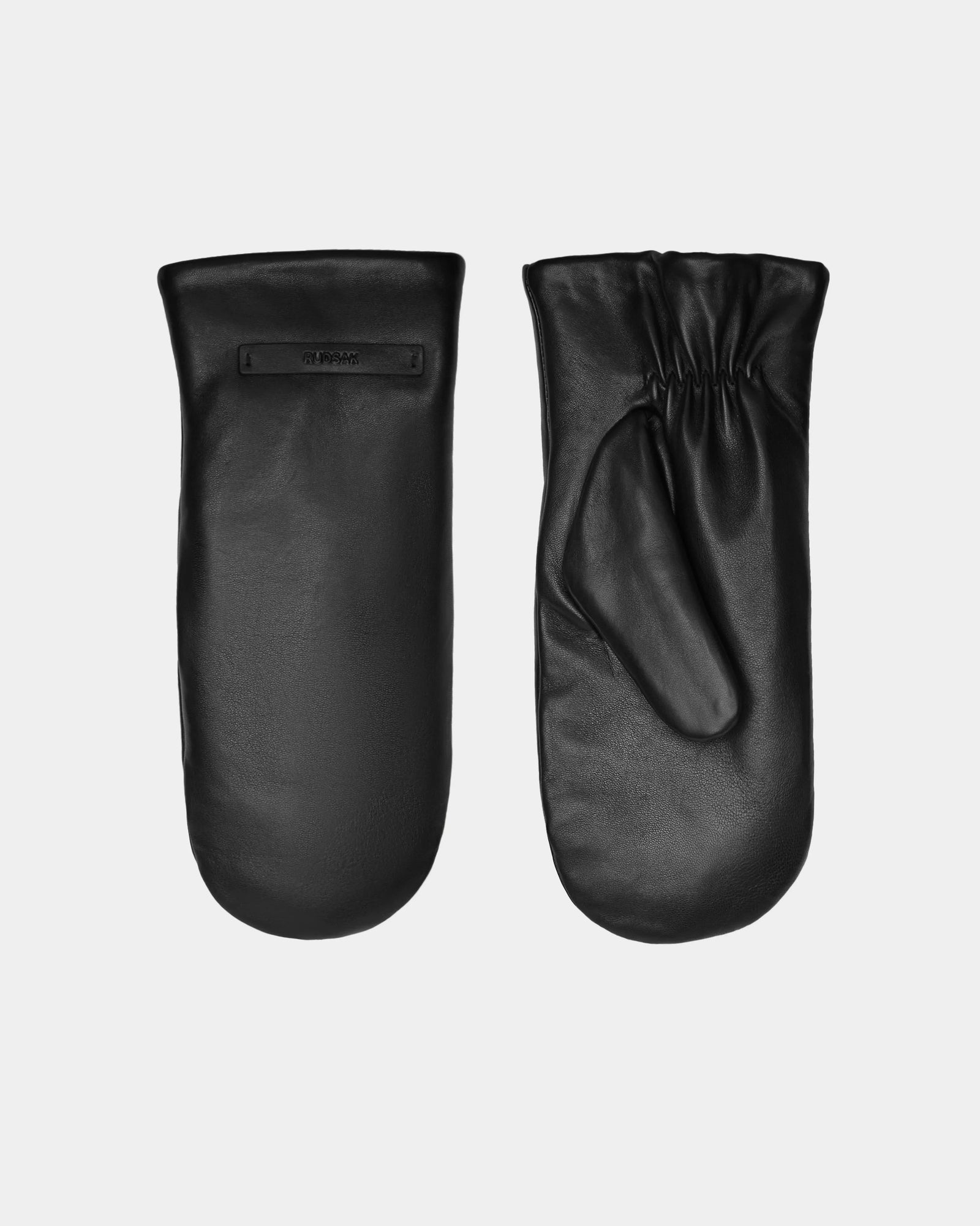 A pair of Rudsak SELMA - 8424508 Black womens leather mittens is displayed: one shows the gathered elastic palm with faux shearling lining, the other reveals a smooth back and small logo tag—perfect for winter warmth.
