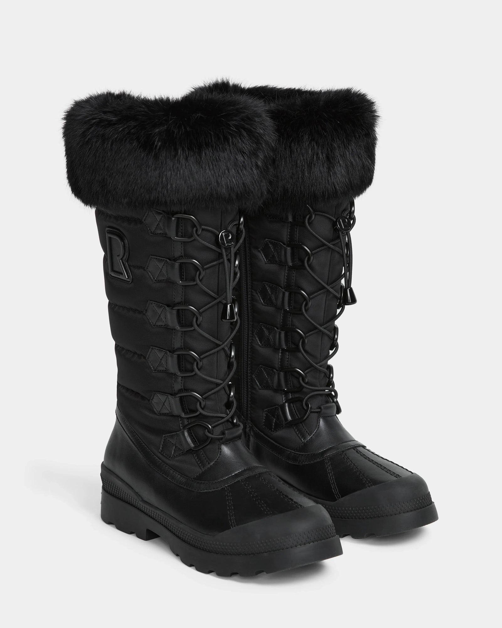 The Rudsak WINDY - L224507 Black boots are tall women's winter boots with faux fur trim, lace-up fronts, rugged soles, quilted sides with a raised R logo, and offer stylish, insulated cold-weather comfort.