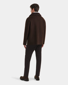 A man faces away, wearing the Rudsak AIDEN - 6125558 Espresso mens wool-blend coat with a textured collar, paired with dark trousers and brown shoes against a plain white background.