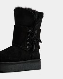 The Rudsak INESA - L225026 Black is a women's suede platform boot with a wool lining, thick sole, and ankle lace-up detail, shown on a plain white background.