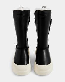 A pair of Rudsak KLAIR L - L225519 black women's leather city boots with white fur lining and thick white soles, shown from the back against a plain, light background.
