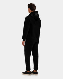 A person stands facing away, wearing the Rudsak LEROY - U525509 Black M cotton-blend unisex hoodie with 