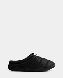 The Rudsak MILTON - M225504 Black is a men’s black slip-on quilted slipper with padding, a textured sole, pull tab, and vegan leather style, shown on a plain light gray background.