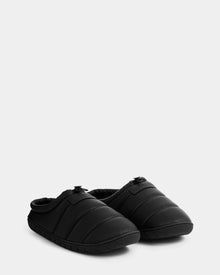 A pair of Rudsak MILTON - M225504 Black men’s quilted slippers with closed toes, textured soles, and soft faux-shearling lining, placed side by side on a light gray background.