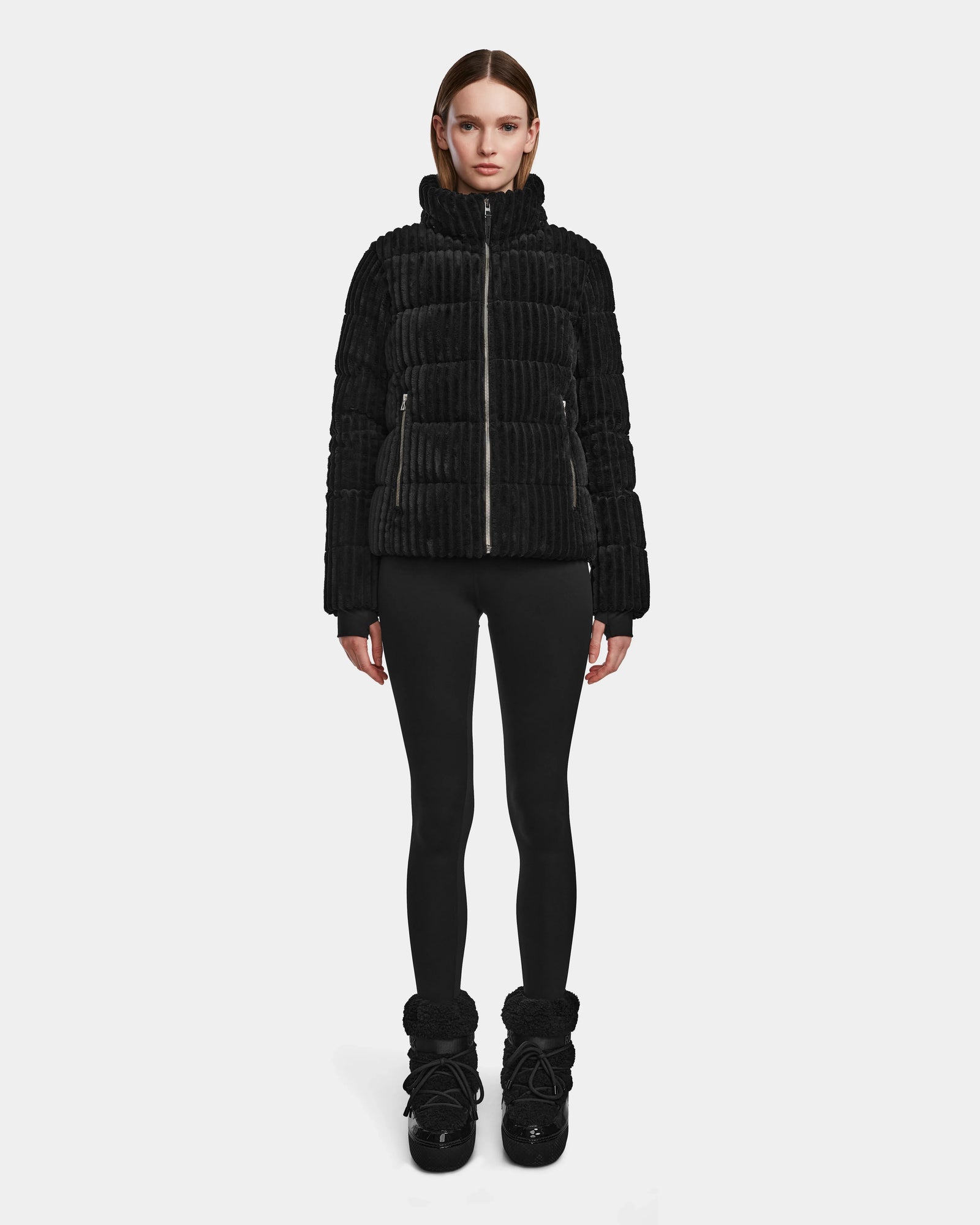 A person stands facing forward, wearing the MIRRY FF - L124507 Black womens short down puffer jacket with black leggings and black winter boots against a plain white background.