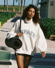Outdoor lifestyle front view of the Crush Sweatshirt in cream, a cream quarter-zip pullover sweatshirt with 