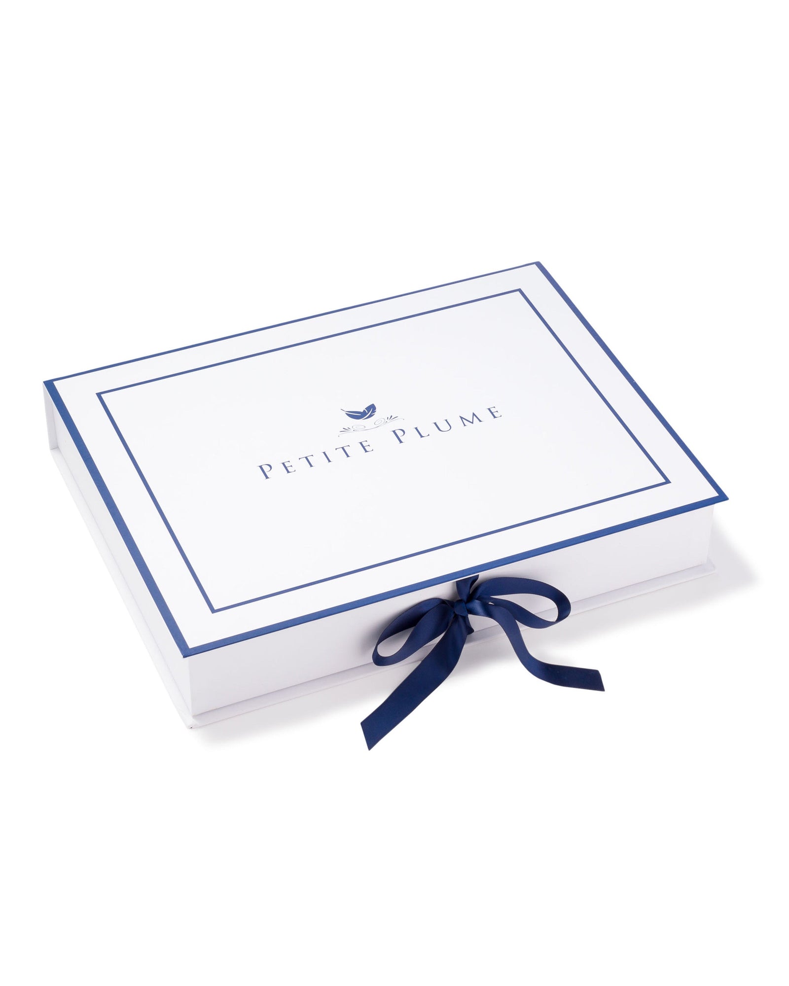 A rectangular white gift box with a blue border elegantly displays the Petite Plume brand, tied with a blue ribbon. The luxury of their Mens Silk Pajama Set in Black Art Nouveau offers the nightly charm of being wrapped in mulberry silk.