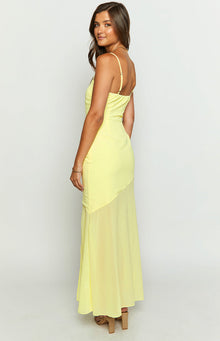 Side view of a yellow chiffon maxi dress with adjustable spaghetti straps, ruched side, and sheer asymmetrical skirt overlay