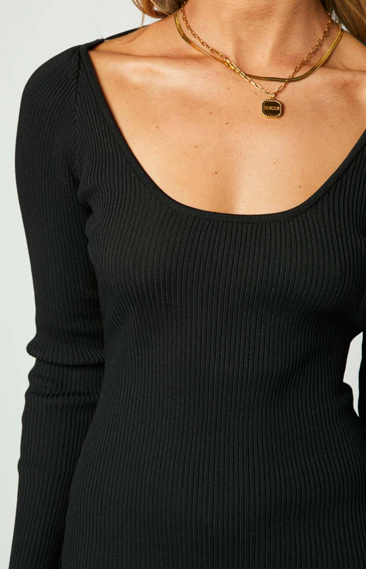 Close-up of the wide scoop neckline and ribbed knit texture of a black long sleeve maxi dress
