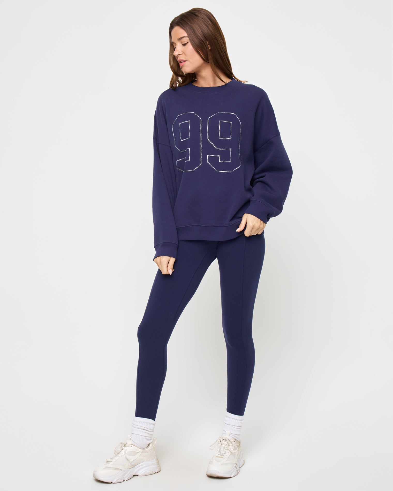 Angled view of the LSPACE Legend Sweatshirt in midnight blue on a model against a light background, showing the rhinestone graphic detail.