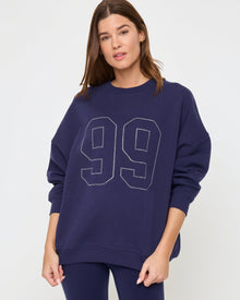 Close-up detail view of the LSPACE Legend Sweatshirt in midnight blue on a model, showing the rhinestone graphic and fabric detail of the cropped oversized sweatshirt.