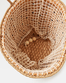 Top-down interior view of the Palma Nights Bag in natural-black showing the open-weave net lining and wooden bead detail at the base.