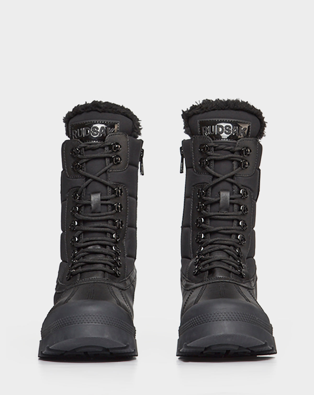 The REAGAN - 6222500 BLACK mens winter boots by Rudsak feature thick soles, lace-up fronts, and faux fur lining at the top. Shown facing forward on a plain white background.