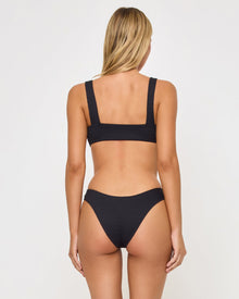 back view of woman wearing a black bikini against a white background