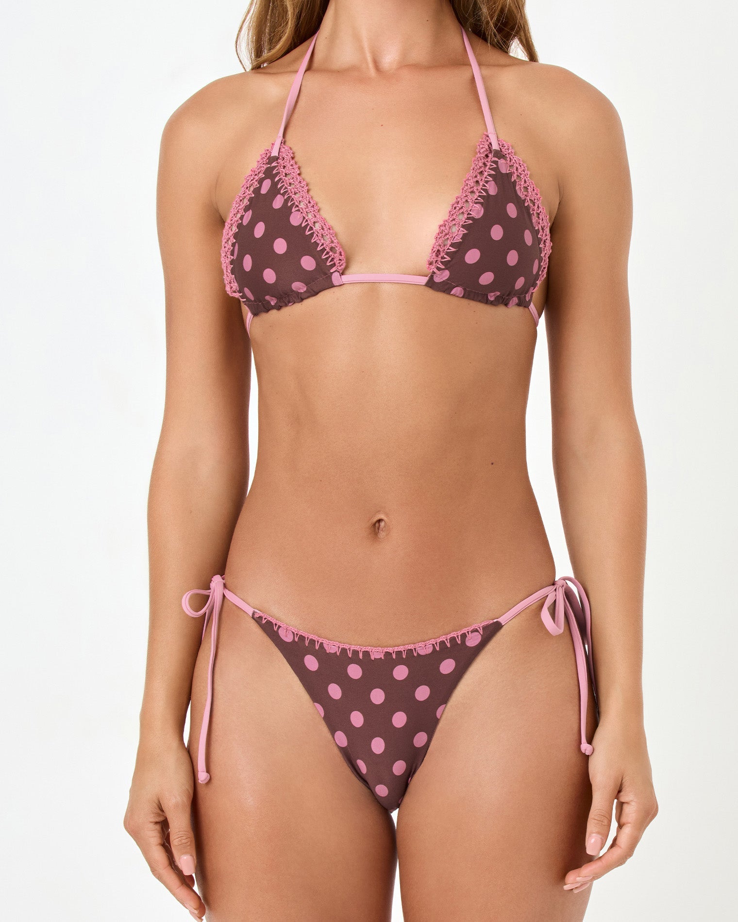 Woman wearing a polka dot bikini with pink and brown pattern on a white background