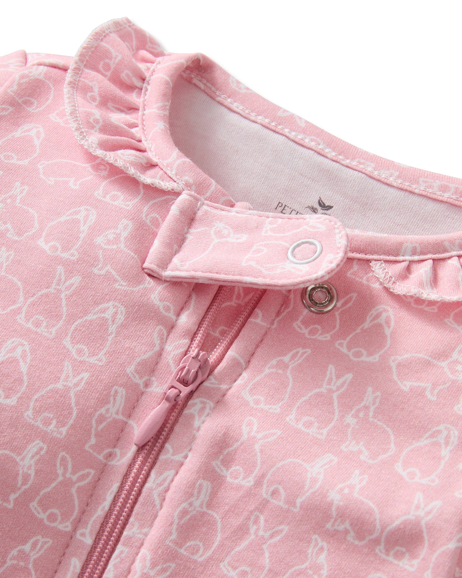 The Baby's Pima Romper in Hoppy Days Pink features long sleeves, white cuffs, a front zipper, a soft white bunny pattern, and a ruffled neckline.