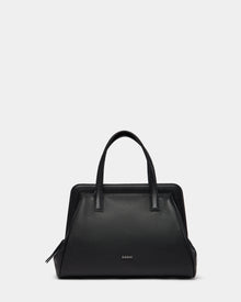 The Rudsak TAULLA - 8325002 Black womens pebble leather satchel features two handles, a spacious interior, and a subtle front logo, shown on a plain light gray background.