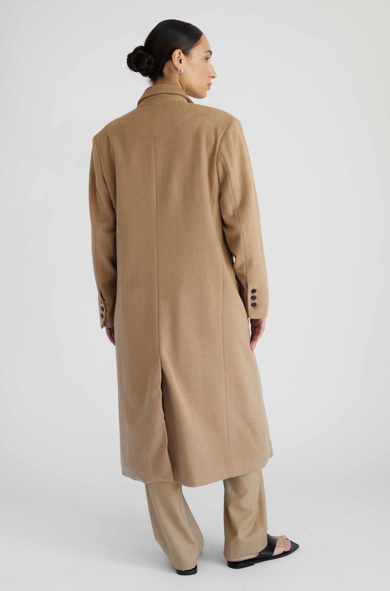 Woman wearing a beige coat on a white background