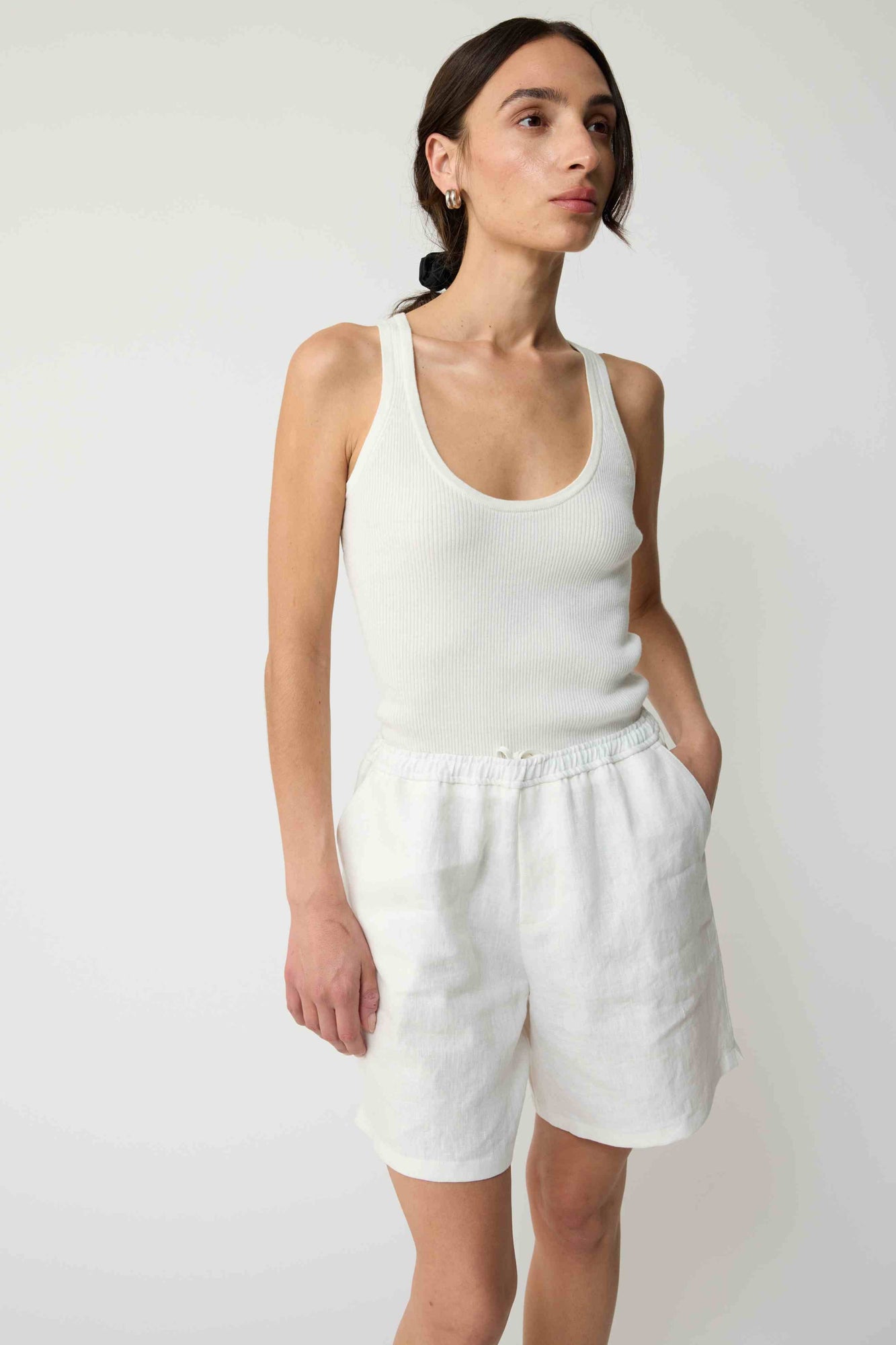 Woman wearing white linen shorts and a white tank top