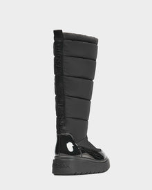 A single black Rudsak CLAUDE - L223506 women's tall quilted winter boot featuring a thick textured sole, glossy toe and heel accents, and a vertical rear pull tab with raised RUDSAK branding.