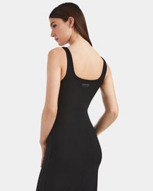A woman with straight brown hair models contemporary elegance in the Rudsak WANDA - 8524035 Black, a fitted sleeveless black dress in stretch performance fabric, shown from the back and side against a plain white background.