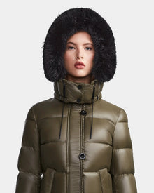 A person models the Rudsak MEYA S - L123521 Light Olive women’s down puffer jacket with a large black faux fur-trimmed hood, facing forward against a plain light gray background.